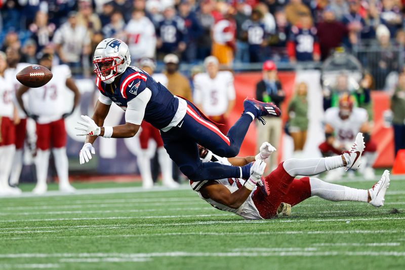 New England Patriots wide receiver JuJu Smith-Schuster (7) bobbles the pass while defended by Washington Commanders cornerback Kendall Fuller (29) during the second half an NFL football game on Sunday, Nov. 5, 2023, in Foxborough, Mass. (AP Photo/Greg M. Cooper)