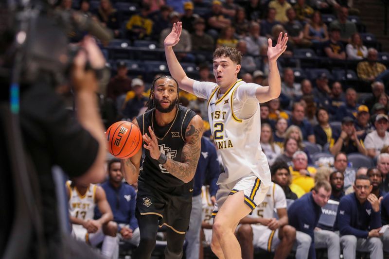 Mar 6, 2026; Morgantown, West Virginia, USA; UCF Knights forward Jordan Burks (99) dribbles baseline against West Virginia Mountaineers guard Treysen Eaglestaff (52) during the first half at Hope Coliseum. Mandatory Credit: Ben Queen-Imagn Images