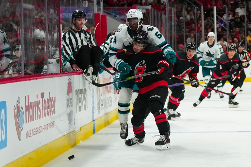 Oct 27, 2023; Raleigh, North Carolina, USA; Carolina Hurricanes center Seth Jarvis (24) checks San Jose Sharks right wing Givani Smith (54) during the second period at PNC Arena. Mandatory Credit: James Guillory-USA TODAY Sports