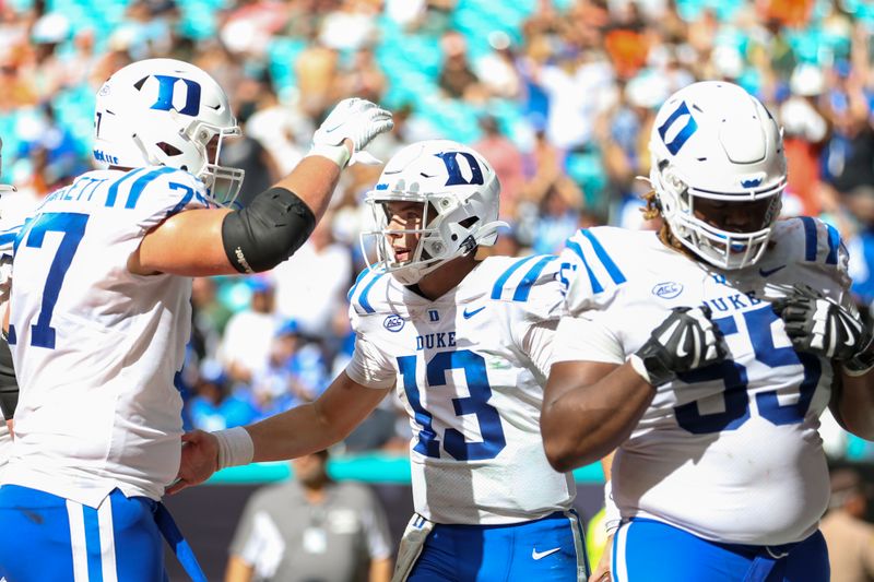 Oct 22, 2022; Miami Gardens, Florida, USA; Duke Blue Devils quarterback Riley Leonard (13) celebrates with offensive lineman Justin Pickett (77) after scoring a touchdown during the fourth quarter against the Miami Hurricanes at Hard Rock Stadium. Mandatory Credit: Sam Navarro-USA TODAY Sports