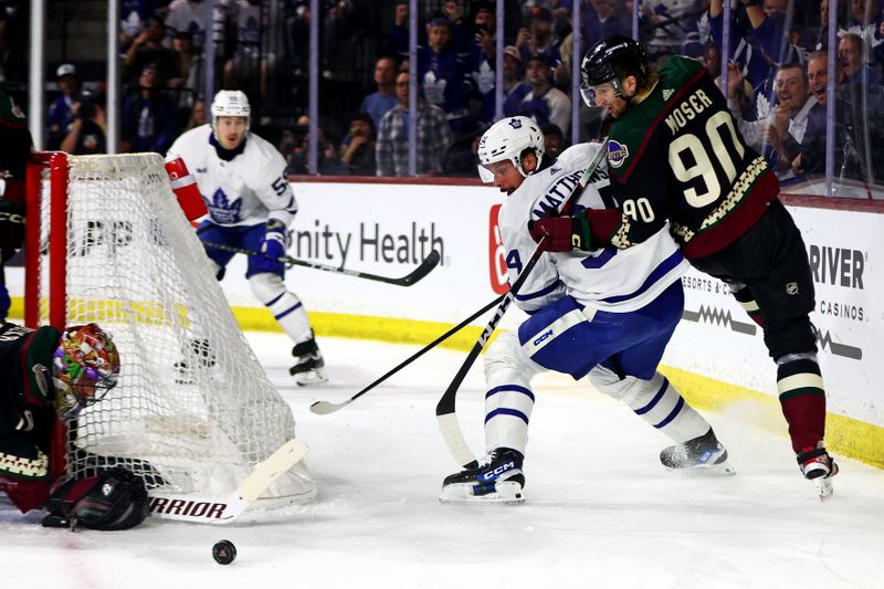 Feb 21, 2024; Tempe, Arizona, USA; Toronto Maple Leafs center Auston Matthews (34) and Arizona Coyotes defenseman J.J. Moser (90) go for the puck during the first period at Mullett Arena. Mandatory Credit: Mark J. Rebilas-USA TODAY Sports