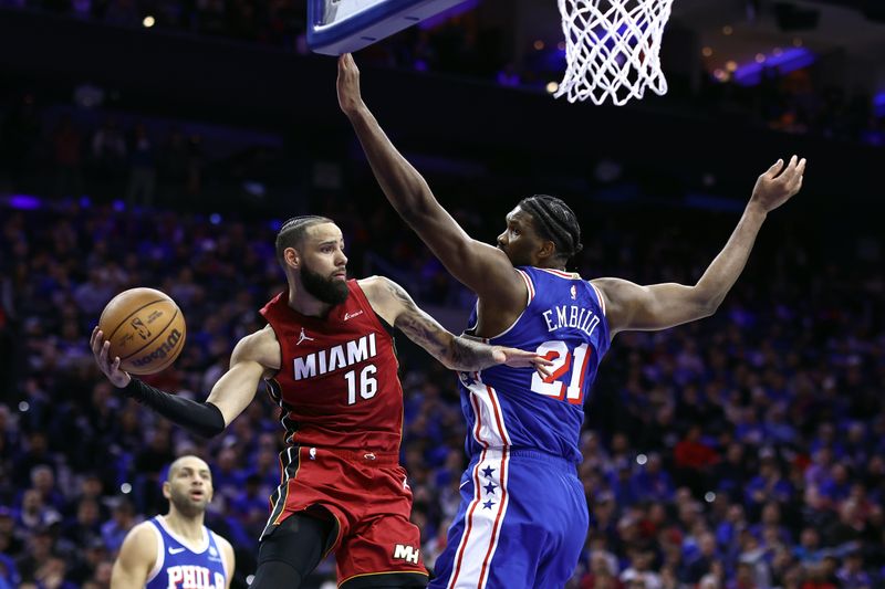 PHILADELPHIA, PENNSYLVANIA - APRIL 17: Caleb Martin #16 of the Miami Heat passes the ball past Joel Embiid #21 of the Philadelphia 76ers during the third quarter of the Eastern Conference Play-In Tournament at the Wells Fargo Center on April 17, 2024 in Philadelphia, Pennsylvania. NOTE TO USER: User expressly acknowledges and agrees that, by downloading and or using this photograph, User is consenting to the terms and conditions of the Getty Images License Agreement. (Photo by Tim Nwachukwu/Getty Images)