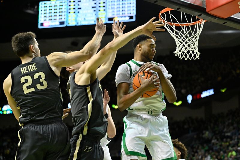 Jan 18, 2025; Eugene, Oregon, USA; Oregon Ducks forward Kwame Evans Jr. (10) grabs a rebound from Purdue Boilermakers forward Camden Heide (23) and forward Raleigh Burgess (34) during the second half at Matthew Knight Arena. Mandatory Credit: Craig Strobeck-Imagn Images