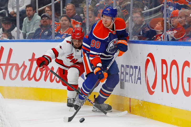 Oct 22, 2024; Edmonton, Alberta, CAN; Edmonton Oilers forward Corey Perry (90) and Carolina Hurricanes defensemen Shayne Gostisbehere (4) battle along the boards for a loose puck during the third period at Rogers Place. Mandatory Credit: Perry Nelson-Imagn Images