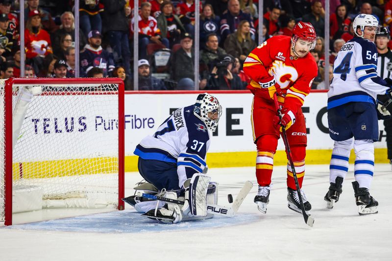 Nov 15, 2025; Calgary, Alberta, CAN; Winnipeg Jets goaltender Connor Hellebuyck (37) guards his net as Calgary Flames center Rory Kerins (6) tries to score during the second period at Scotiabank Saddledome. Mandatory Credit: Sergei Belski-Imagn Images