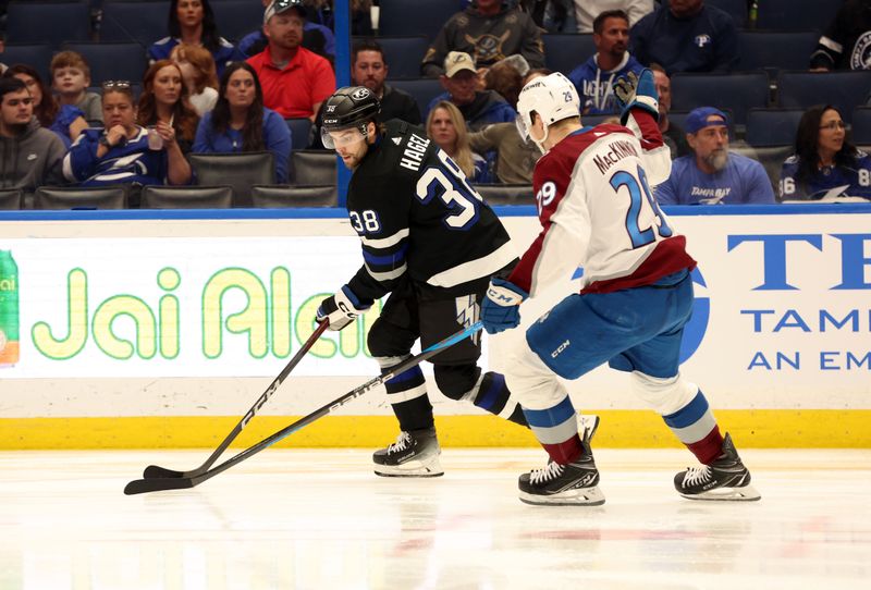 Feb 15, 2024; Tampa, Florida, USA; Tampa Bay Lightning lewdt wing Brandon Hagel, (38) skates with the puck as Colorado Avalanche center Nathan MacKinnon (29) defends  during the third period at Amalie Arena. Mandatory Credit: Kim Klement Neitzel-USA TODAY Sports