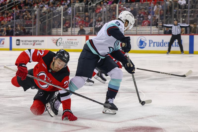 Dec 6, 2024; Newark, New Jersey, USA; Seattle Kraken center Chandler Stephenson (9) skates with the puck while being defended by New Jersey Devils defenseman Brett Pesce (22) during the first period at Prudential Center. Mandatory Credit: Ed Mulholland-Imagn Images