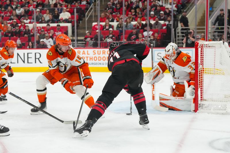 Jan 8, 2026; Raleigh, North Carolina, USA;  Carolina Hurricanes left wing Taylor Hall (71) tries to control the puck against Anaheim Ducks defenseman Drew Helleson (14) and goaltender Ville Husso (33) during the first period at Lenovo Center. Mandatory Credit: James Guillory-Imagn Images