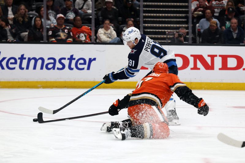 Feb 27, 2026; Anaheim, California, USA;  Winnipeg Jets center Cole Perfetti (91) and Anaheim Ducks defenseman Radko Gudas (7) fight for the puck during the second period at Honda Center. Mandatory Credit: Kiyoshi Mio-Imagn Images
