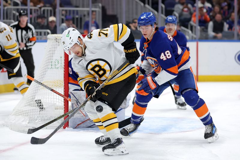 Nov 4, 2025; Elmont, New York, USA; Boston Bruins left wing Viktor Arvidsson (71) plays the puck against New York Islanders defenseman Matthew Schaefer (48) during the first period at UBS Arena. Mandatory Credit: Brad Penner-Imagn Images