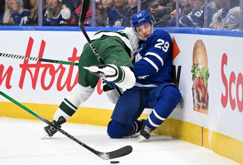 Jan 29, 2025; Toronto, Ontario, CAN;  Toronto Maple Leafs forward Pontus Holmberg (29) is bodychecked by Minnesota Wild defenseman Jon Merrill (4) in the first period at Scotiabank Arena. Mandatory Credit: Dan Hamilton-Imagn Images