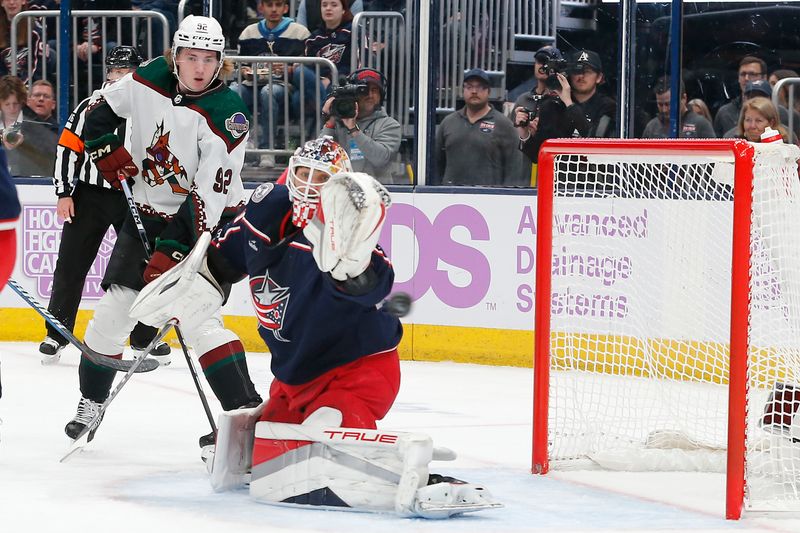 Nov 16, 2023; Columbus, Ohio, USA; Columbus Blue Jackets goalie Elvis Merzlikins (90) makes a save with Arizona Coyotes center Logan Cooley (92) looking for a rebound during the first period at Nationwide Arena. Mandatory Credit: Russell LaBounty-USA TODAY Sports