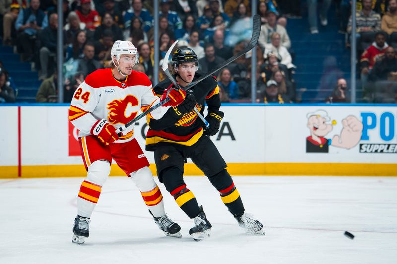 Oct 9, 2025; Vancouver, British Columbia, CAN; Calgary Flames defenseman Jake Bean (24) battles with Vancouver Canucks forward Braeden Cootes (80) in the second period at Rogers Arena. Mandatory Credit: Bob Frid-Imagn Images