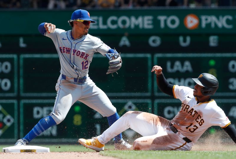 Jul 7, 2024; Pittsburgh, Pennsylvania, USA;  New York Mets shortstop Francisco Lindor (12) turns a double play over Pittsburgh Pirates third baseman Ke'Bryan Hayes (13) during the seventh inning at PNC Park. The Mets won 3-2. Mandatory Credit: Charles LeClaire-USA TODAY Sports