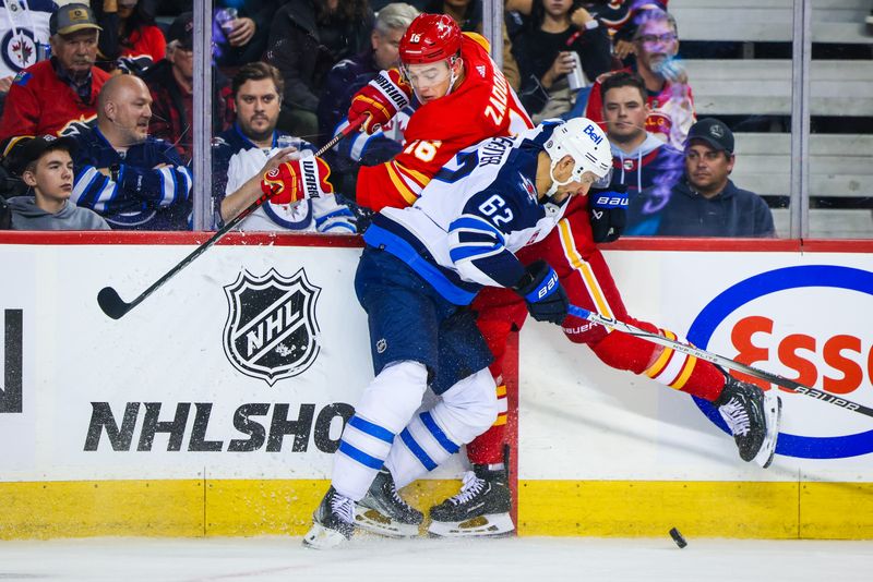 Oct 11, 2023; Calgary, Alberta, CAN; Winnipeg Jets right wing Nino Niederreiter (62) and Calgary Flames defenseman Nikita Zadorov (16) battle for the puck during the third period at Scotiabank Saddledome. Mandatory Credit: Sergei Belski-USA TODAY Sports