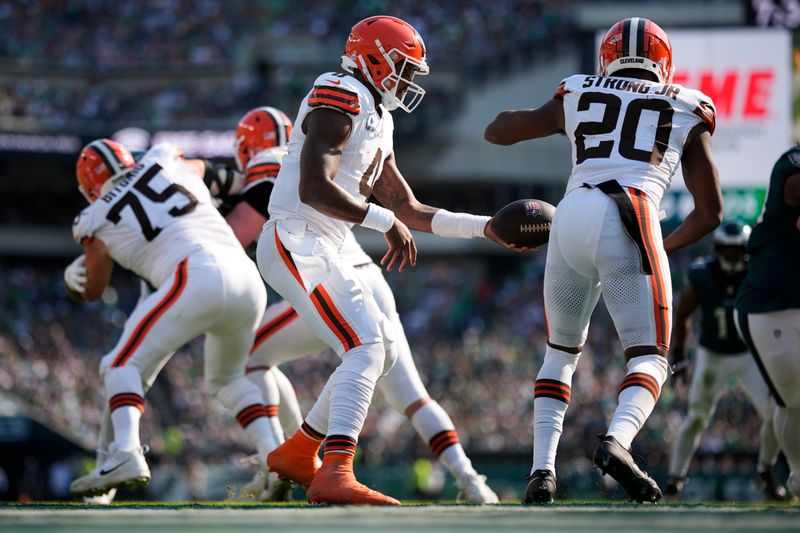 Cleveland Browns quarterback Deshaun Watson (4) hands off the ball to Browns running back Pierre Strong Jr. (20) during the second half of an NFL football game against the Philadelphia Eagles on Sunday, Oct. 13, 2024, in Philadelphia. (AP Photo/Matt Slocum)