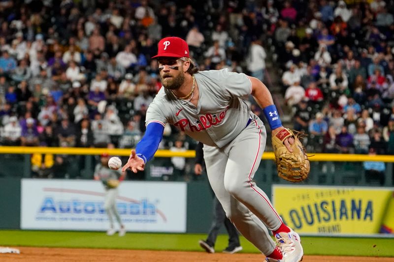 May 25, 2024; Denver, Colorado, USA;  Philadelphia Phillies first base Bryce Harper (3) flips the ball to fist base for an out at Coors Field. Mandatory Credit: Michael Madrid-USA TODAY Sports