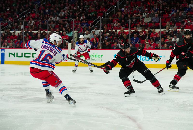 Mar 12, 2024; Raleigh, North Carolina, USA; New York Rangers center Vincent Trocheck (16) gets the shot away against Carolina Hurricanes center Jordan Staal (11) during the second period at PNC Arena. Mandatory Credit: James Guillory-USA TODAY Sports