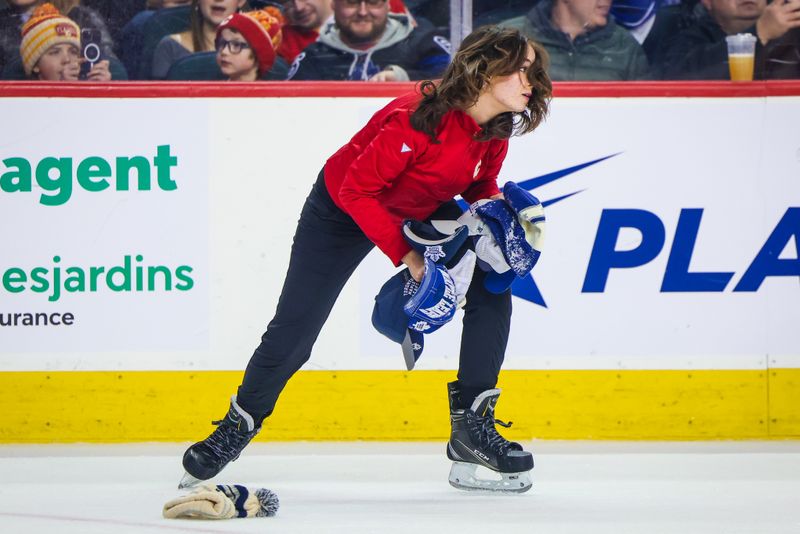 Jan 18, 2024; Calgary, Alberta, CAN; Calgary Flames ice crew members collect hats thrown on the ice for Toronto Maple Leafs center Auston Matthews (34) goal during the second period against the Calgary Flames at Scotiabank Saddledome. Mandatory Credit: Sergei Belski-USA TODAY Sports