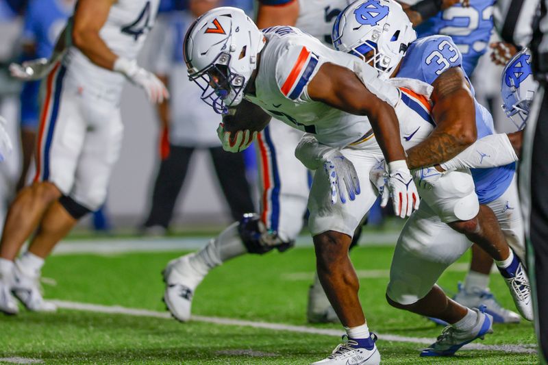 Oct 21, 2023; Chapel Hill, North Carolina, USA; Virginia Cavaliers running back Mike Hollins (7) fights for yards as he is tackled by North Carolina Tar Heels linebacker Cedric Gray (33) in the second half at Kenan Memorial Stadium. Mandatory Credit: Nell Redmond-USA TODAY Sports