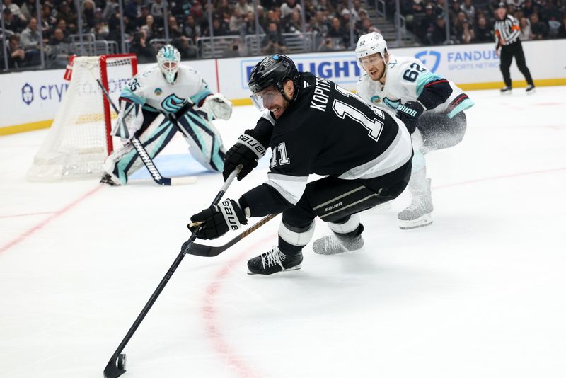 Nov 23, 2024; Los Angeles, California, USA;  Los Angeles Kings center Anze Kopitar (11) controls the puck as Seattle Kraken defenseman Brandon Montour (62) defends during the second period at Crypto.com Arena. Mandatory Credit: Kiyoshi Mio-Imagn Images