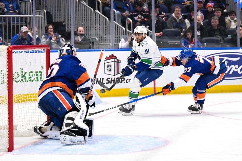 Dec 19, 2025; Elmont, New York, USA; Vancouver Canucks left wing Evander Kane (91) skates with the puck while defended by New York Islanders defenseman Tony Deangelo (77) during the third period at UBS Arena. Mandatory Credit: John Jones-Imagn Images