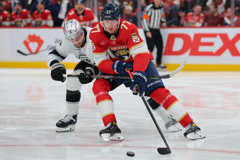 Dec 17, 2025; Sunrise, Florida, USA; Florida Panthers defenseman Niko Mikkola (77) moves the puck against Los Angeles Kings right wing Adrian Kempe (9) during the third period at Amerant Bank Arena. Mandatory Credit: Sam Navarro-Imagn Images