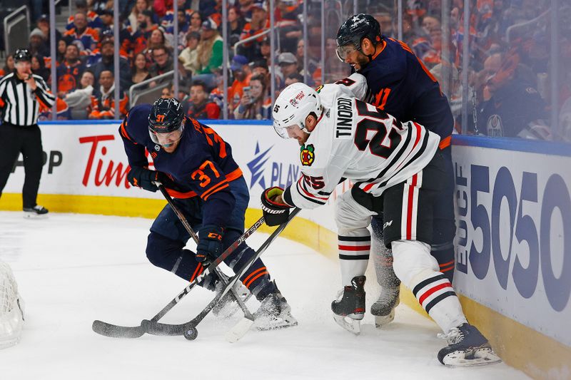 Jan 25, 2024; Edmonton, Alberta, CAN; Edmonton Oilers forward Warren Foegele (37) and Chicago Blackhawks defensemen Jarred Tinordi (25) battle for a loose puck during the third period at Rogers Place. Mandatory Credit: Perry Nelson-USA TODAY Sports