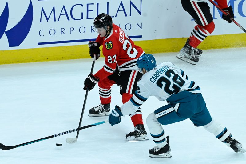 Jan 16, 2024; Chicago, Illinois, USA; Chicago Blackhawks left wing Lukas Reichel (27) moves the puck against San Jose Sharks center Ryan Carpenter (22) during the second period at United Center. Mandatory Credit: Matt Marton-USA TODAY Sports