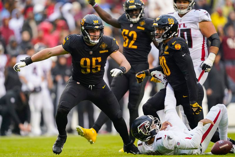 Atlanta Falcons quarterback Marcus Mariota (1) on the ground after being sacked by Washington Commanders defensive ends Casey Toohill (95) and Montez Sweat (90) during the second half of an NFL football game, Sunday, Nov. 27, 2022, in Landover, Md. (AP Photo/Patrick Semansky)