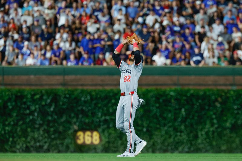 Aug 5, 2024; Chicago, Illinois, USA; Minnesota Twins outfielder Austin Martin (82) catches a fly ball hit by Chicago Cubs second baseman Nico Hoerner during the fifth inning at Wrigley Field. Mandatory Credit: Kamil Krzaczynski-USA TODAY Sports