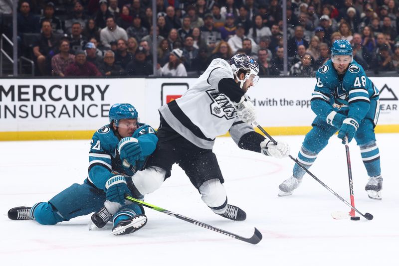 Dec 27, 2023; Los Angeles, California, USA; Los Angeles Kings center Phillip Danault (24) gets tangled up with San Jose Sharks right wing Mitchell Russell (64) during the second period of a game at Crypto.com Arena. Mandatory Credit: Jessica Alcheh-USA TODAY Sports