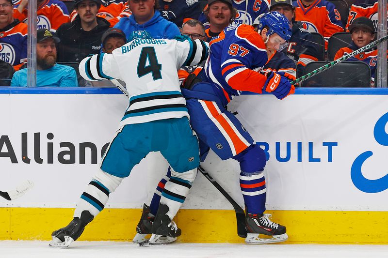 Apr 15, 2024; Edmonton, Alberta, CAN; Edmonton Oilers forward Connor McDavid (97) and San Jose Sharks defensemen Kyle Burroughs (4) battle along the boards for a loose puck during the first period at Rogers Place. Mandatory Credit: Perry Nelson-USA TODAY Sports