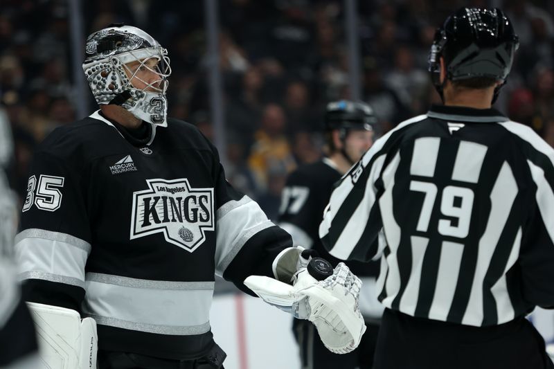 Nov 21, 2025; Los Angeles, California, USA;  Los Angeles Kings goaltender Darcy Kuemper (35) hands a puck to linesman Kiel Murchison (79) during the third period against the Boston Bruins at Crypto.com Arena. Mandatory Credit: Kiyoshi Mio-Imagn Images