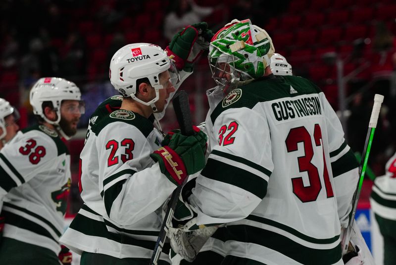 Jan 21, 2024; Raleigh, North Carolina, USA;  Minnesota Wild goaltender Filip Gustavsson (32) and center Marco Rossi (23) celebrate their victory against the Carolina Hurricanes at PNC Arena. Mandatory Credit: James Guillory-USA TODAY Sports