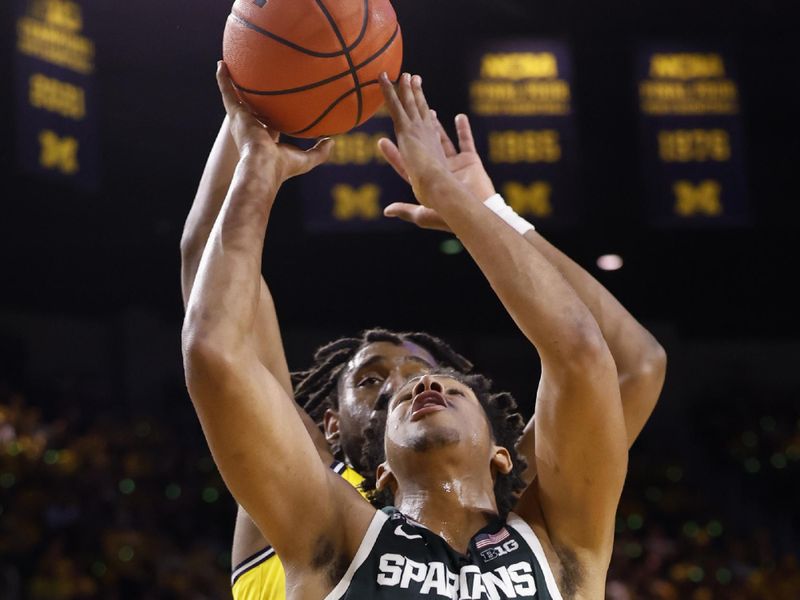 Feb 18, 2023; Ann Arbor, Michigan, USA;  Michigan State Spartans guard A.J. Hoggard (11) shoots the ball against Michigan Wolverines forward Tarris Reed Jr. (32) in the second half at Crisler Center. Mandatory Credit: Rick Osentoski-USA TODAY Sports