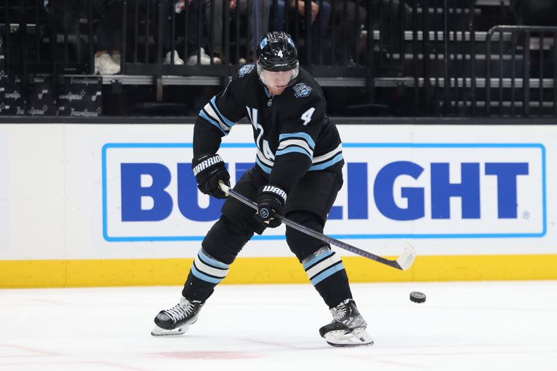 Nov 18, 2024; Salt Lake City, Utah, USA; Utah Hockey Club defenseman Juuso Valimaki (4) plays the puck against the Washington Capitals during the third period at Delta Center. Mandatory Credit: Rob Gray-Imagn Images