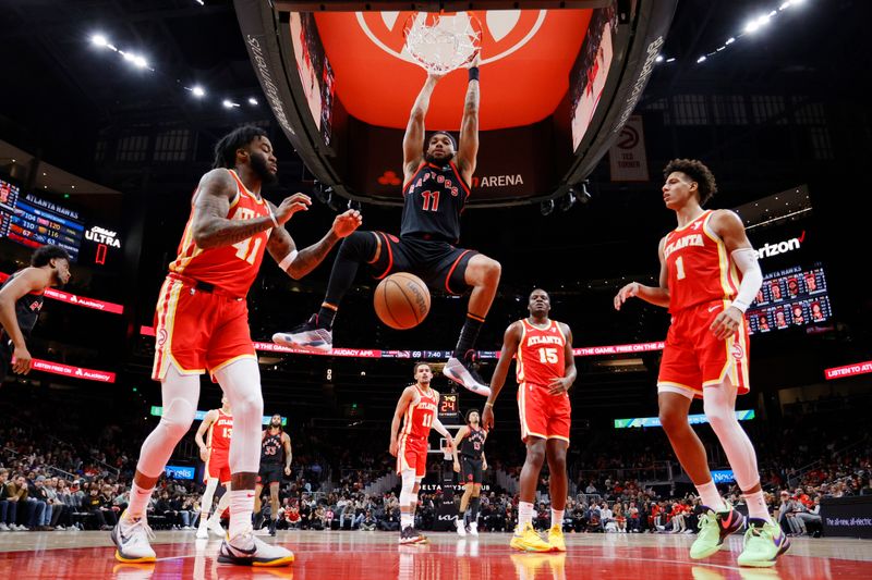 ATLANTA, GEORGIA - JANUARY 28: Bruce Brown #11 of the Toronto Raptors dunks over Saddiq Bey #41 and Jalen Johnson #1 of the Atlanta Hawks during the half at State Farm Arena on January 28, 2024 in Atlanta, Georgia. NOTE TO USER: User expressly acknowledges and agrees that, by downloading and or using this photograph, User is consenting to the terms and conditions of the Getty Images License Agreement. (Photo by Alex Slitz/Getty Images)