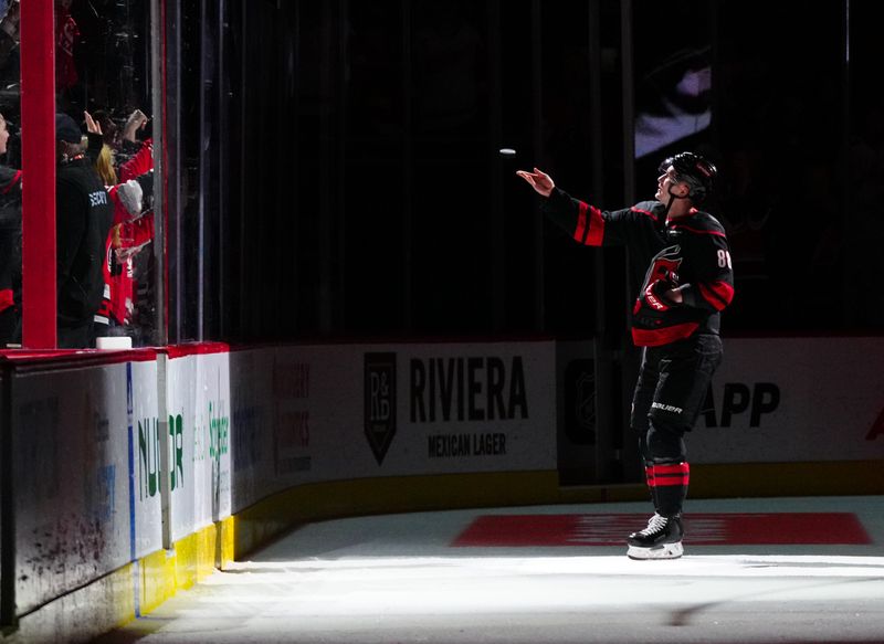 Jan 19, 2024; Raleigh, North Carolina, USA; Carolina Hurricanes center Martin Necas (88) tosses a puck into the stands after their victory against the Detroit Red Wings at PNC Arena. Mandatory Credit: James Guillory-USA TODAY Sports