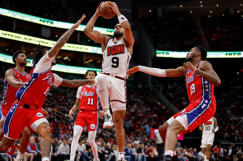 HOUSTON, TEXAS - MARCH 17: Dillon Brooks #9 of the Houston Rockets goes up for a lay up between Justin Edwards #19 and Jalen Hood-Schifino #17 of the Philadelphia 76ers in the second half at Toyota Center on March 17, 2025 in Houston, Texas.  NOTE TO USER: User expressly acknowledges and agrees that, by downloading and/or using this photograph, user is consenting to the terms and conditions of the Getty Images License Agreement.  (Photo by Tim Warner/Getty Images)