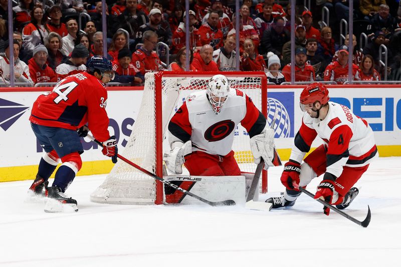 Dec 11, 2025; Washington, District of Columbia, USA; Washington Capitals right wing Justin Sourdif (34) shoots the puck on Carolina Hurricanes goaltender Brandon Bussi (32) as Hurricanes defenseman Shayne Gostisbehere (4) defends during the first period at Capital One Arena. Mandatory Credit: Geoff Burke-Imagn Images