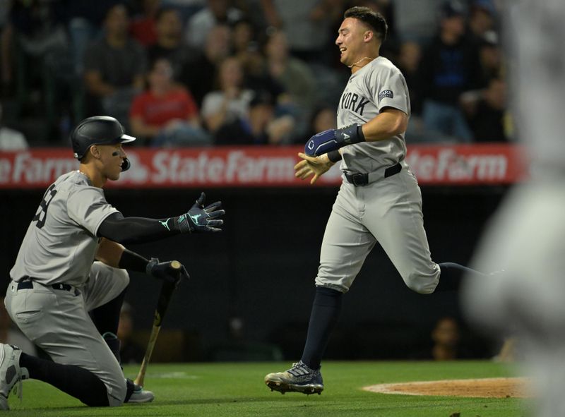 May 30, 2024; Anaheim, California, USA;  New York Yankees shortstop Anthony Volpe (11) is met by center fielder Aaron Judge (99) as he scores on a triple by right fielder Juan Soto (22) in the seventh inning against the Los Angeles Angels at Angel Stadium. Mandatory Credit: Jayne Kamin-Oncea-USA TODAY Sports