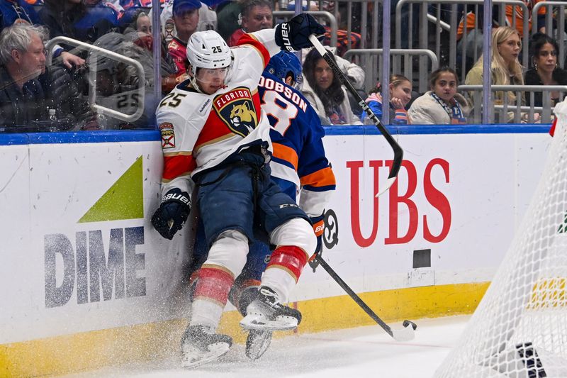 Oct 26, 2024; Elmont, New York, USA;  Florida Panthers right wing Mackie Samoskevich (25) and New York Islanders defenseman Noah Dobson (8) collide along the boards during the first period at UBS Arena. Mandatory Credit: Dennis Schneidler-Imagn Images