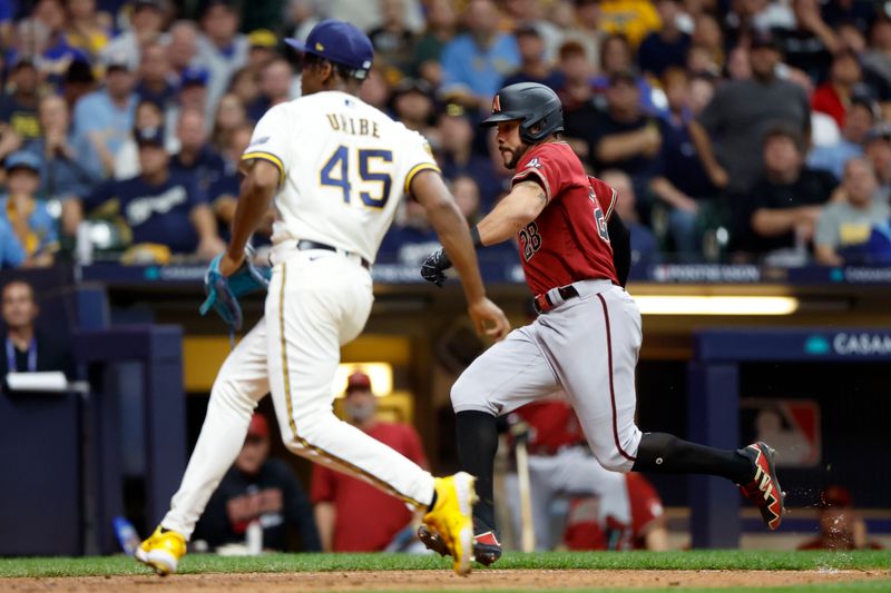 Oct 4, 2023; Milwaukee, Wisconsin, USA; Arizona Diamondbacks left fielder Tommy Pham (28) scores against Milwaukee Brewers relief pitcher Abner Uribe (45) on a wild pitch in the sixth inning during game two of the Wildcard series for the 2023 MLB playoffs at American Family Field. Mandatory Credit: Kamil Krzaczynski-USA TODAY Sports