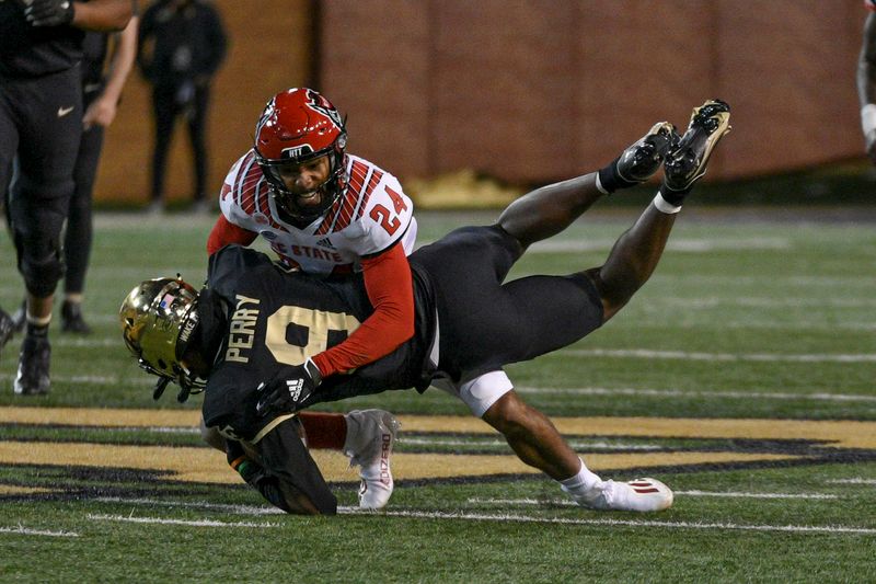 Nov 13, 2021; Winston-Salem, North Carolina, USA; North Carolina State Wolfpack cornerback Derrek Pitts Jr. (24) tackles Wake Forest Demon Deacons wide receiver A.T. Perry (9) during the second half at Truist Field. Mandatory Credit: William Howard-USA TODAY Sports