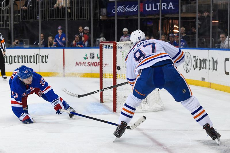 Dec 22, 2023; New York, New York, USA;  Edmonton Oilers center Connor McDavid (97) misses an empty net defended by New York Rangers defenseman Adam Fox (23) during the third period at Madison Square Garden. Mandatory Credit: Dennis Schneidler-USA TODAY Sports