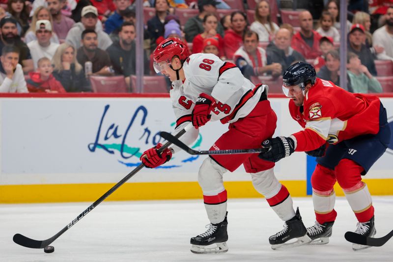 Nov 30, 2024; Sunrise, Florida, USA; Carolina Hurricanes center Martin Necas (88) moves the puck past Florida Panthers defenseman Nate Schmidt (88) during the first period at Amerant Bank Arena. Mandatory Credit: Sam Navarro-Imagn Images