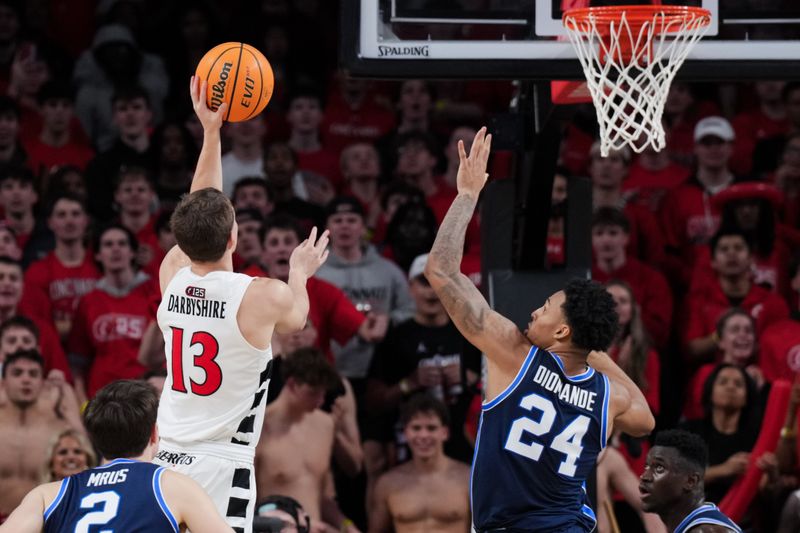 Mar 3, 2026; Cincinnati, Ohio, USA;  Cincinnati Bearcats guard Grant Darbyshire (13) drives to the basket against BYU Cougars forward Dominique Diomande (24) in the second half at Fifth Third Arena. Mandatory Credit: Aaron Doster-Imagn Images