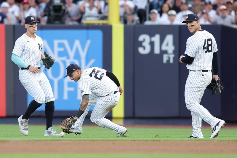 Jun 7, 2024; Bronx, New York, USA; New York Yankees second baseman Gleyber Torres (25) picks up a pop up he dropped for an error by Los Angeles Dodgers third baseman Enrique Hernandez (not pictured) in front of Yankees right fielder Aaron Judge (99) and first baseman Anthony Rizzo (48) during the third inning at Yankee Stadium. Mandatory Credit: Brad Penner-USA TODAY Sports