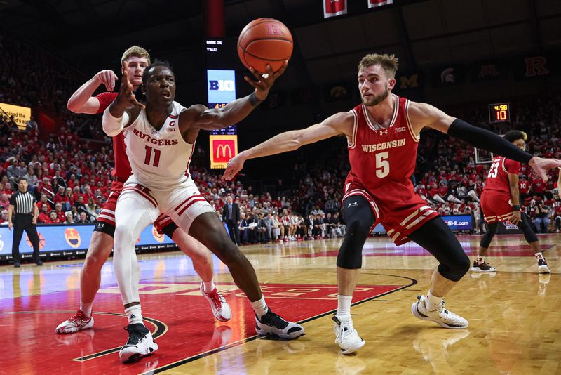 Feb 10, 2024; Piscataway, New Jersey, USA; Rutgers Scarlet Knights center Clifford Omoruyi (11) reaches for the ball against Wisconsin Badgers forward Tyler Wahl (5) and forward Steven Crowl (22) during the second half at Jersey Mike's Arena. Mandatory Credit: Vincent Carchietta-USA TODAY Sports